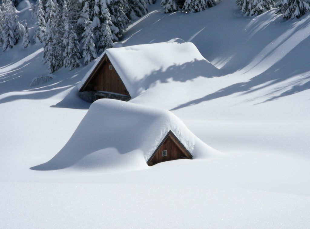 Wooden cabins buried under thick, peaceful snow